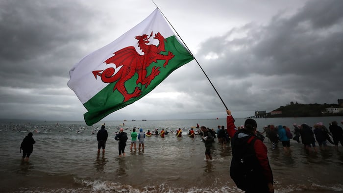 TENBY, WALES - SEPTEMBER 10: A man carries a Welsh flag at the swim leg of IRONMAN Wales on September 10, 2017 in Tenby, Wales. (Photo by Bryn Lennon/Getty Images for IRONMAN)