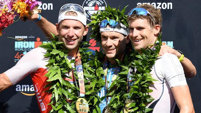 KAILUA KONA, HI - OCTOBER 13: Bart Aernouts of Belgium (2nd place), Patrick Lange of Germany (1st place) and David McNamee of Great Britain (3rd place) celebrate after the IRONMAN World Championships brought to you by Amazon on October 13, 2018 in Kailua Kona, Hawaii. (Photo by Nils Nilsen/Getty Images for IRONMAN)