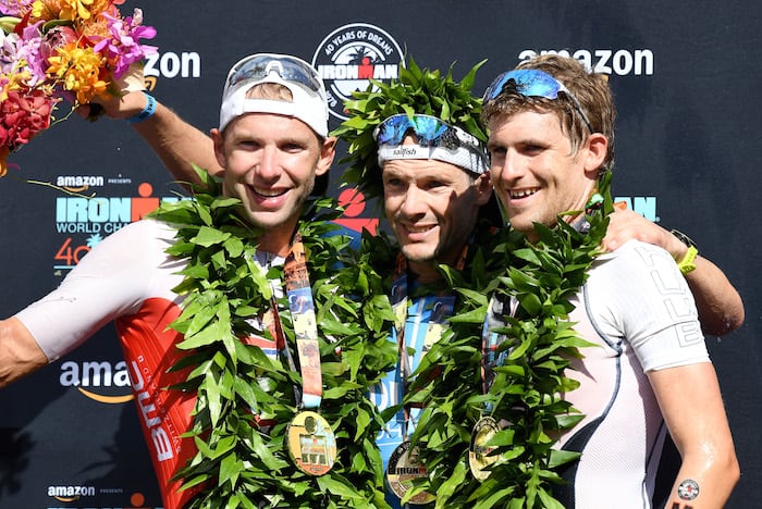 KAILUA KONA, HI - OCTOBER 13: Bart Aernouts of Belgium (2nd place), Patrick Lange of Germany (1st place) and David McNamee of Great Britain (3rd place) celebrate after the IRONMAN World Championships brought to you by Amazon on October 13, 2018 in Kailua Kona, Hawaii. (Photo by Nils Nilsen/Getty Images for IRONMAN)