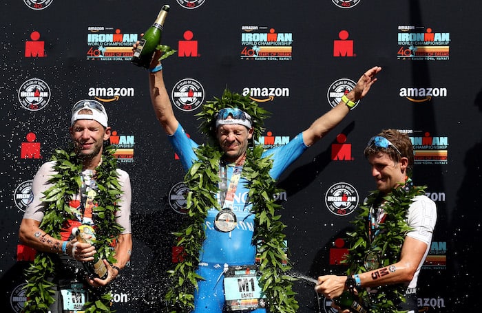 KAILUA KONA, HI - OCTOBER 13: Bart Aernouts of Belgium (2nd place), Patrick Lange of Germany (1st place) and David McNamee of Great Britain (3rd place) celebrate after the IRONMAN World Championships brought to you by Amazon on October 13, 2018 in Kailua Kona, Hawaii. (Photo by Al Bello/Getty Images for IRONMAN)