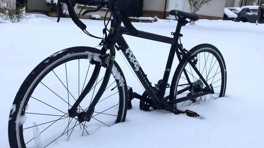 Cyclist riding on a snowy road in cold weather maintaining hydration during winter training