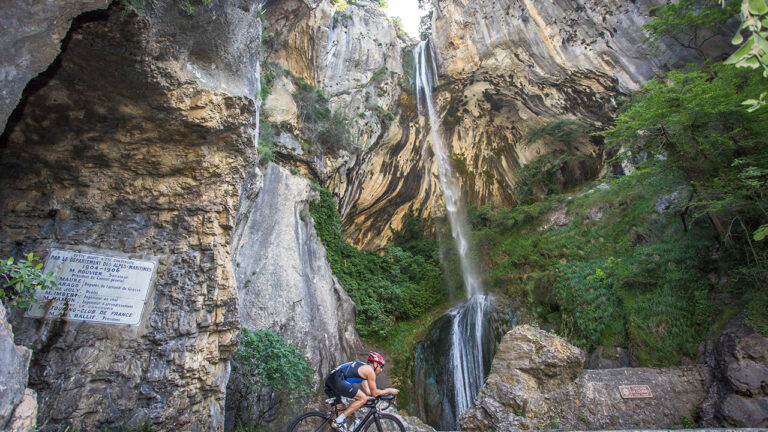 Cyclist rides by a stunning waterfall at Challenge Cagnes-Sur-Mer