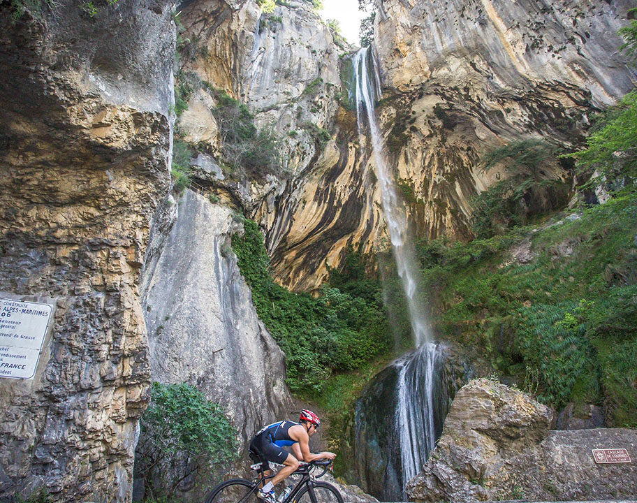 Cyclist rides by a stunning waterfall at Challenge Cagnes-Sur-Mer
