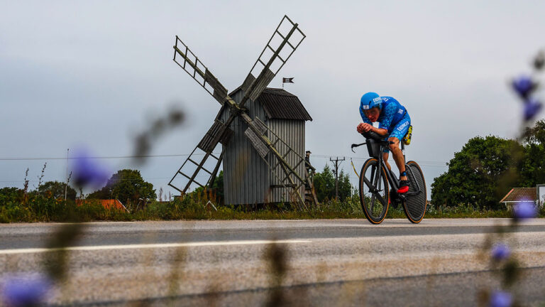 A cyclist rides by a windmill on the bike course of IRONMAN Kalmar