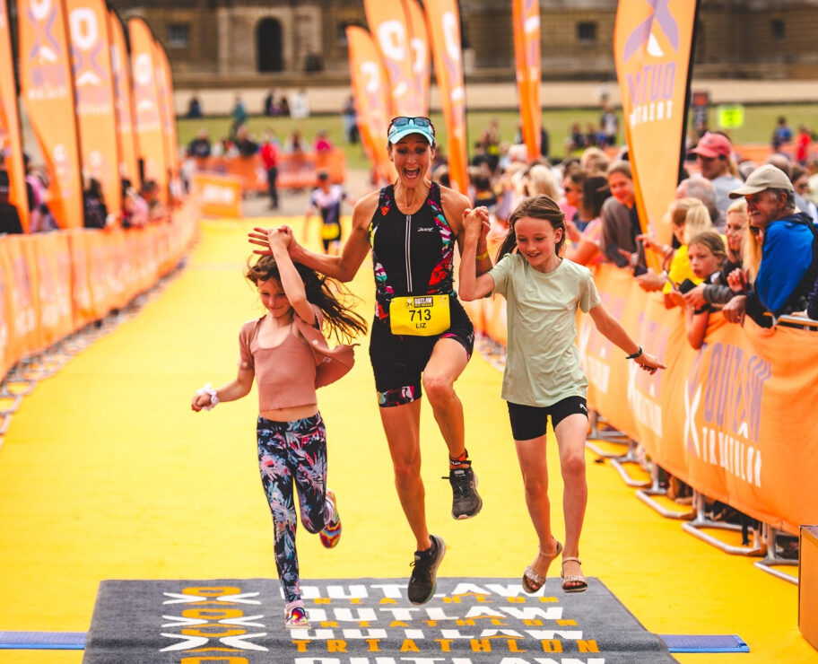 Competitor crosses the finish line with her kids at Outlaw Half Holkham