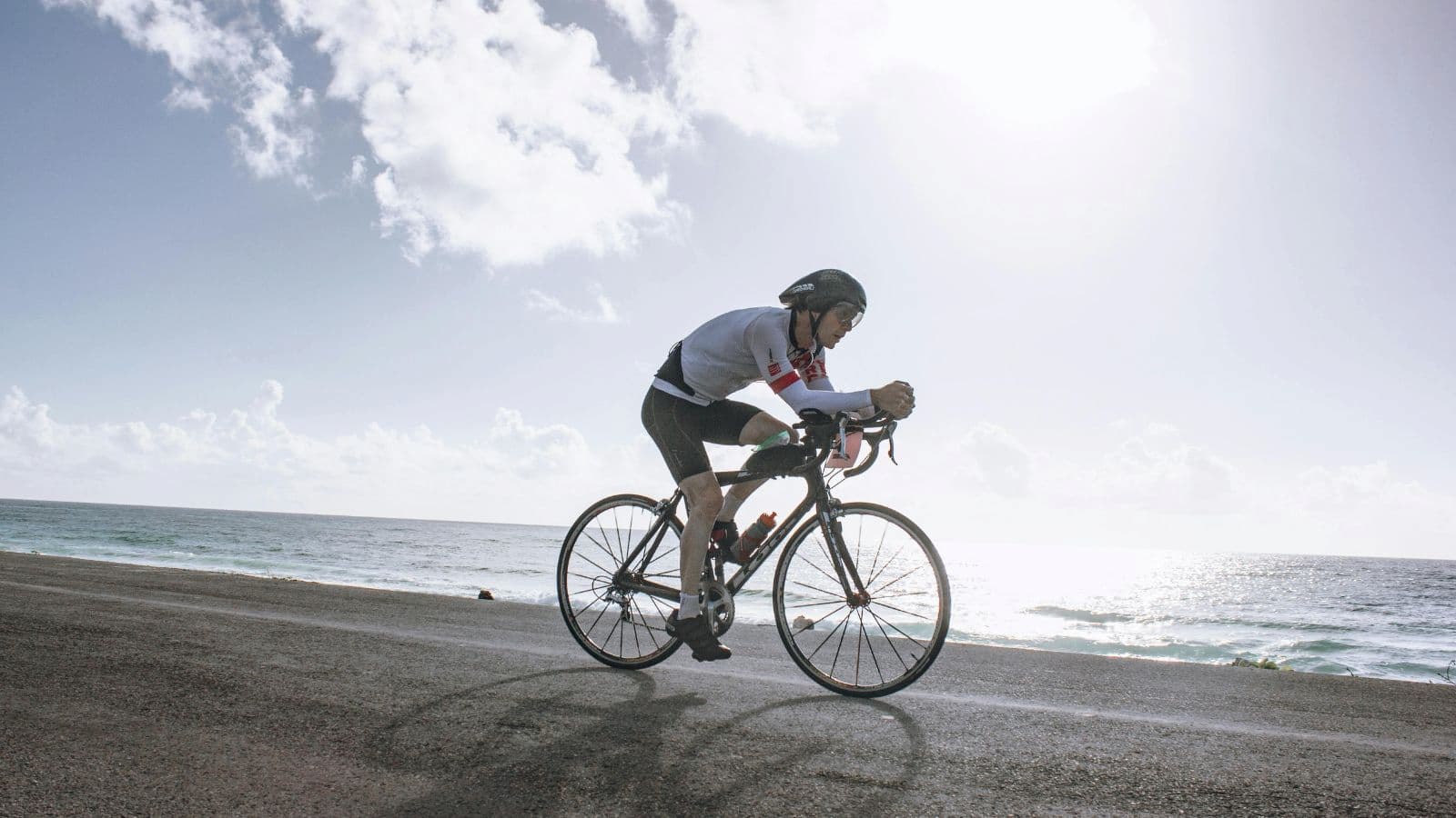 Triathlete cycling on road during race, maintaining steady pace and efficient power output