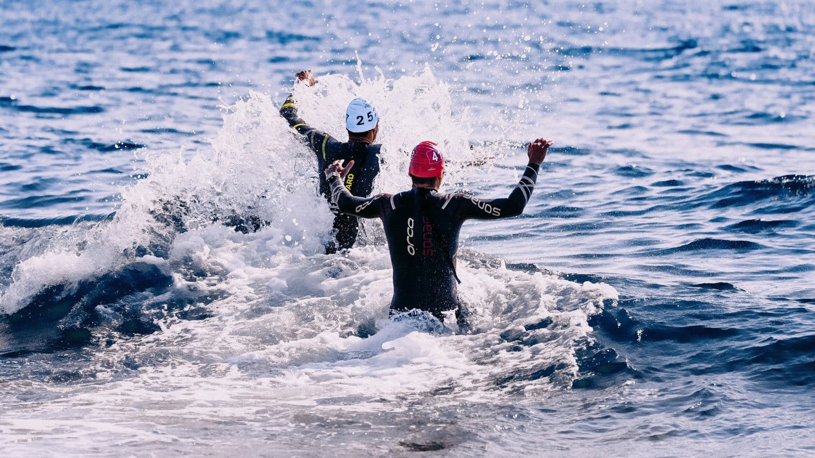 Triathletes swimming in open water during IRONMAN 70.3 race, maintaining controlled rhythm and pacing