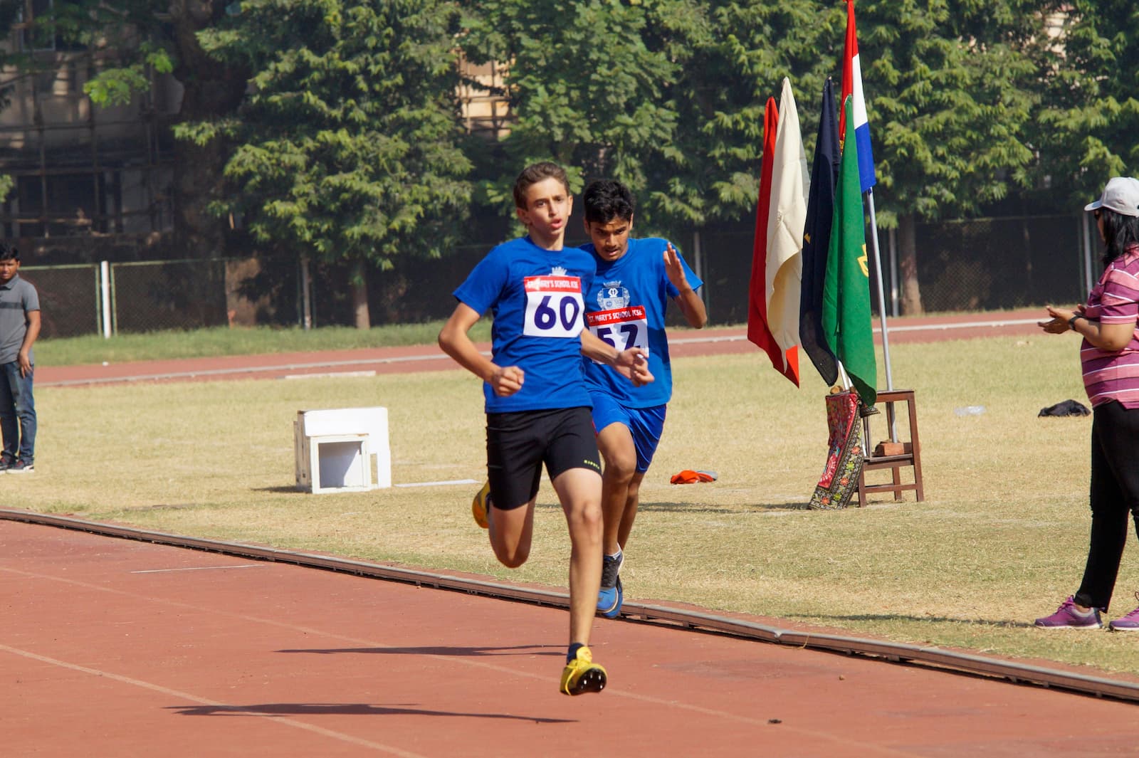 An endurance athlete strides forward during the run segment of a triathlon, showing signs of effort and determination as they compete on a marked race route.