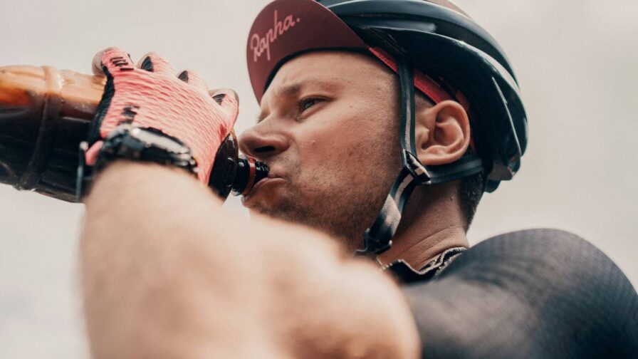 Athlete organizing pre-race nutrition including fruits, hydration drinks, and carbohydrate-rich foods before a triathlon competition