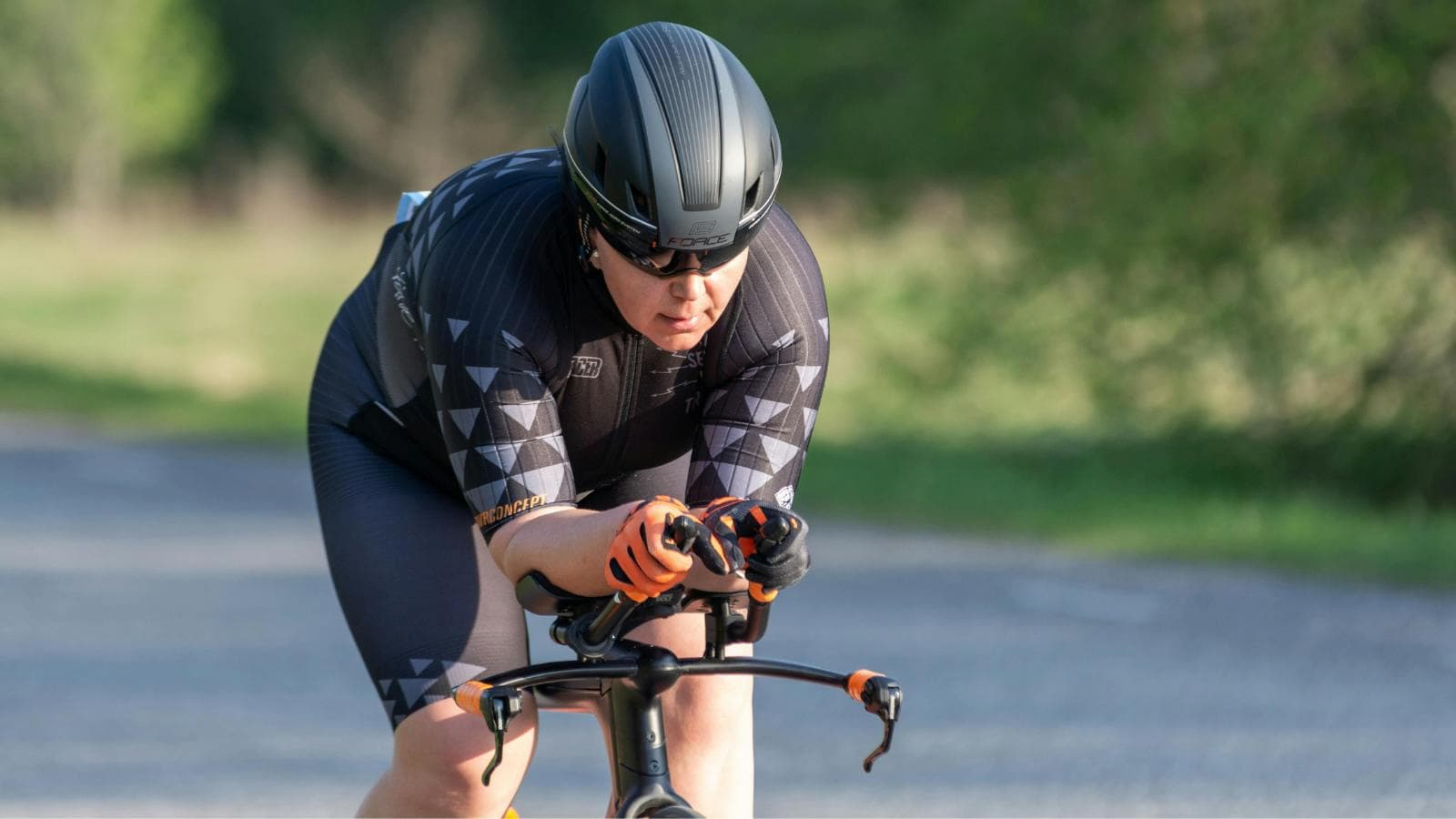 triathlete riding in aero position while fueling regularly to avoid bonking during bike leg