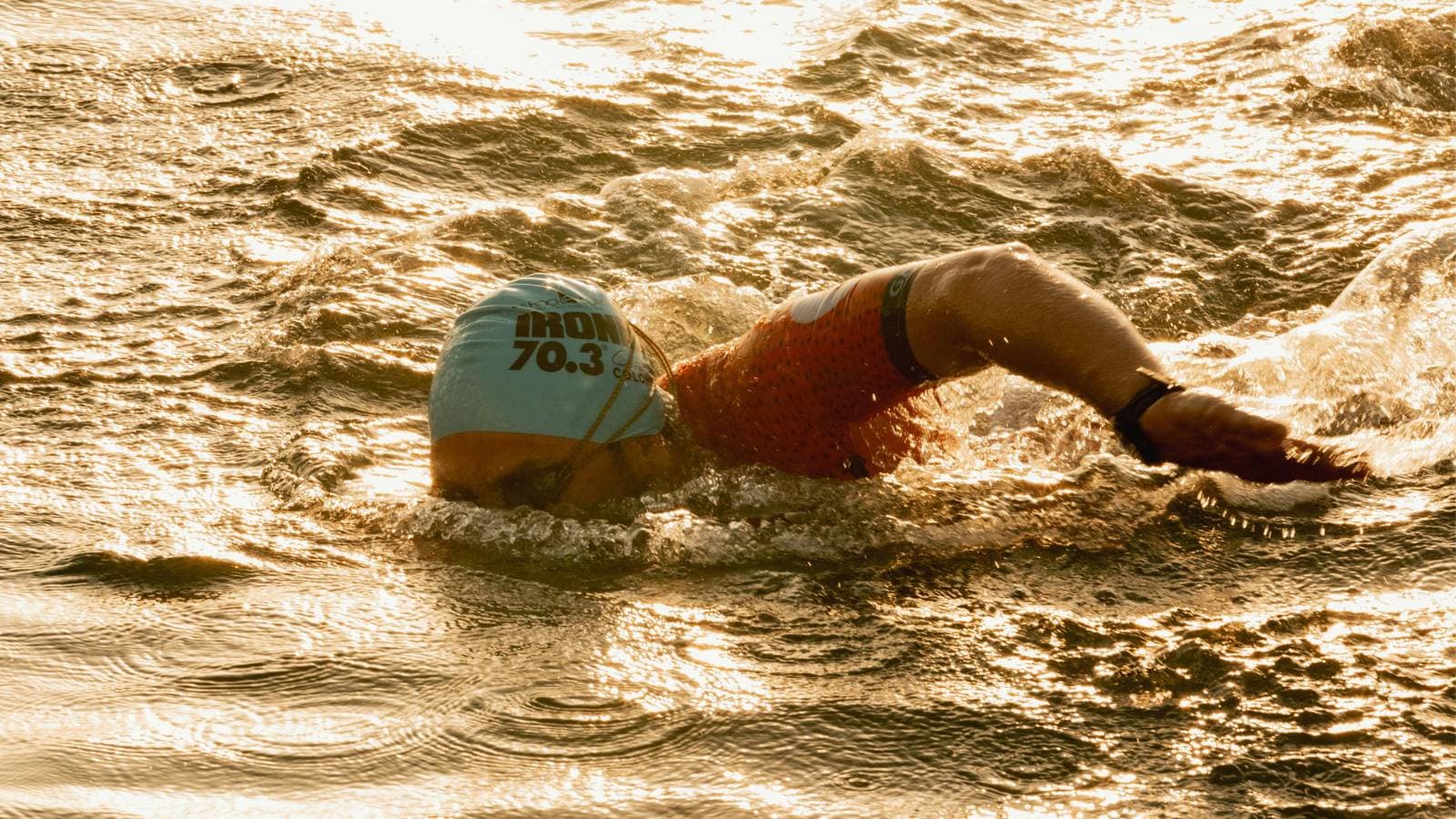 triathlete swimming in open water race maintaining pacing and sighting strategy during half ironman swim segment