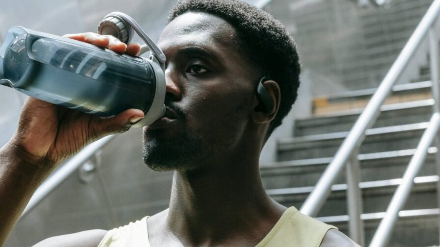 A triathlete drinks an electrolyte drink while exercising outdoors, emphasizing hydration and electrolyte balance for endurance and recovery.