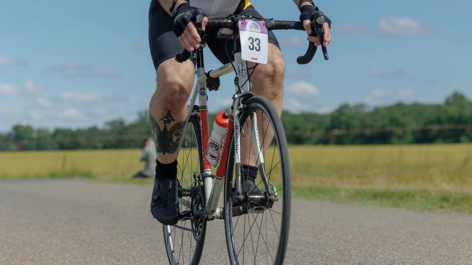 Triathlete cycling on a road bike with power meter displaying FTP data during training session