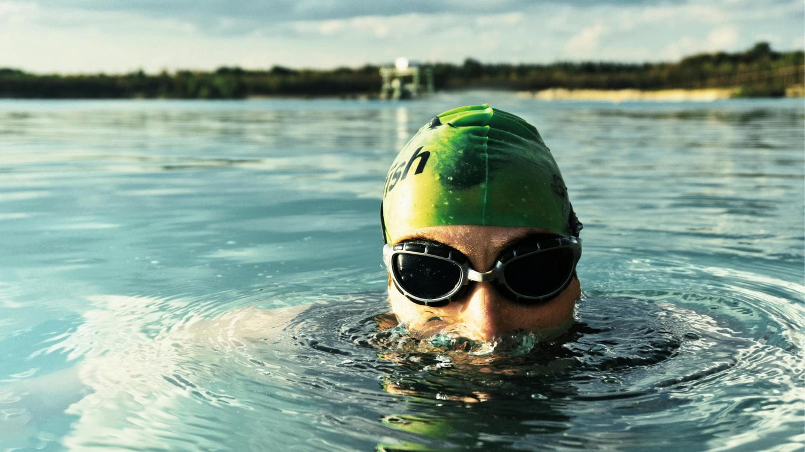 open water swimmer practicing breathing technique during freestyle swimming in lake or ocean