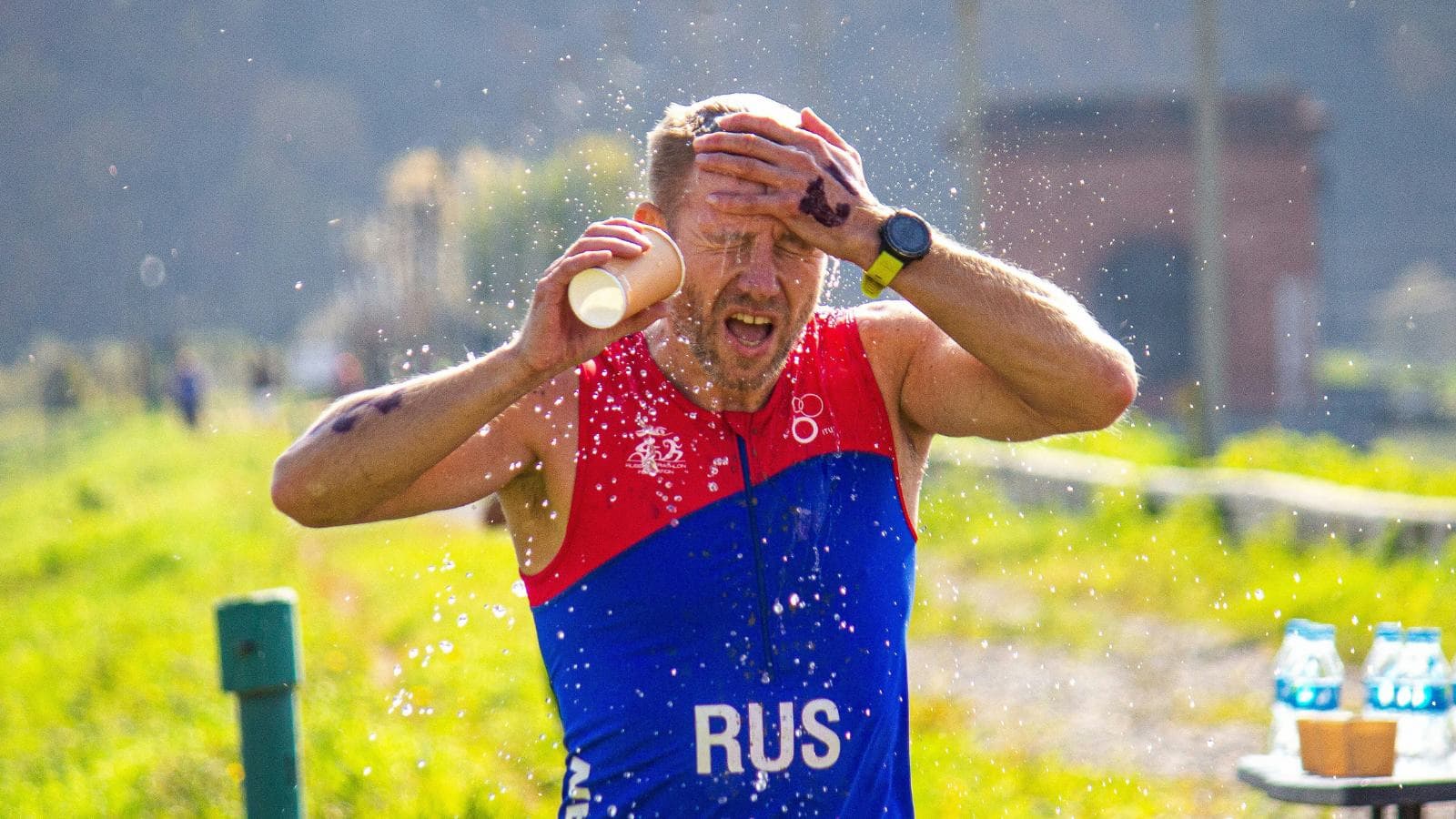 triathlete drinking fluids after race to rehydrate and recover following swim bike run event