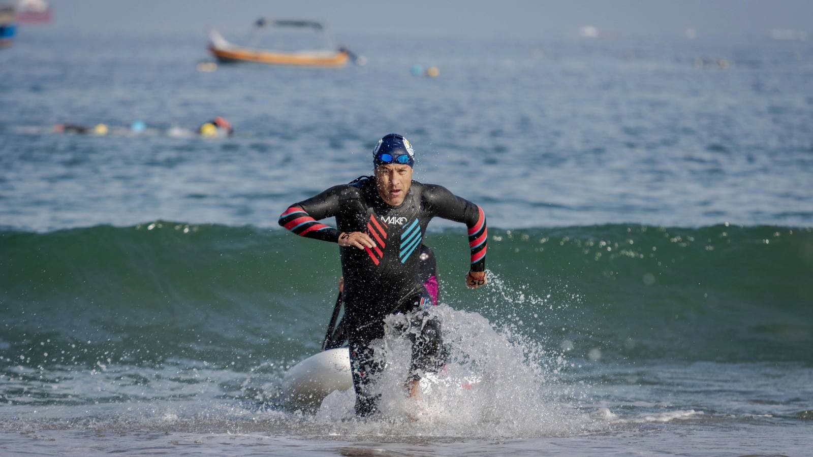 triathlete running out of open water swim toward transition area during race