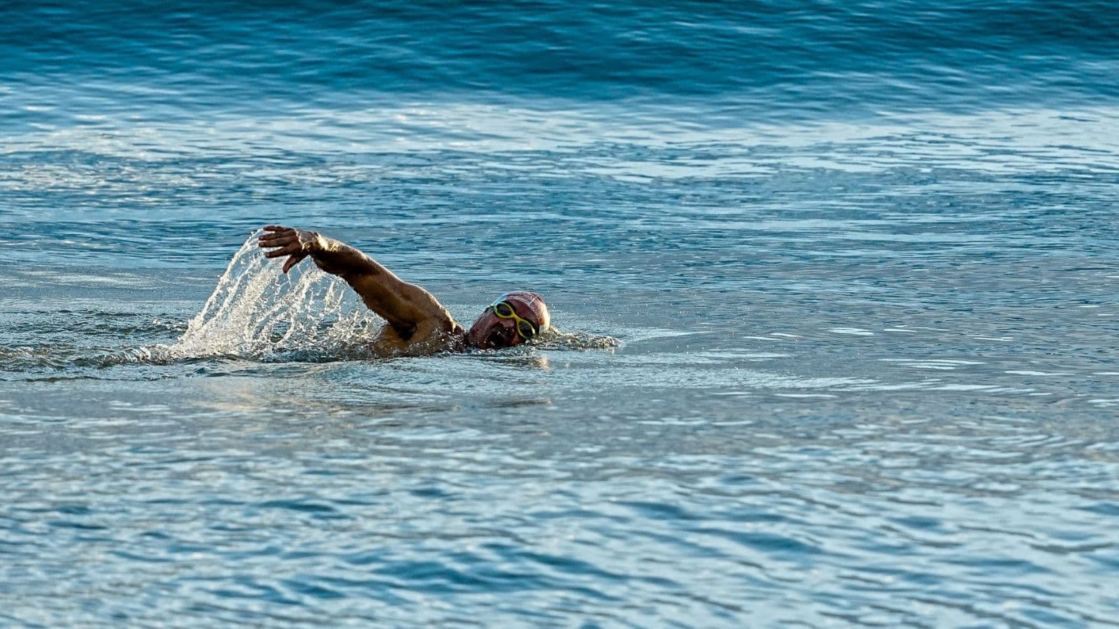 triathlete performing swim drill in pool to improve freestyle technique and swimming efficiency