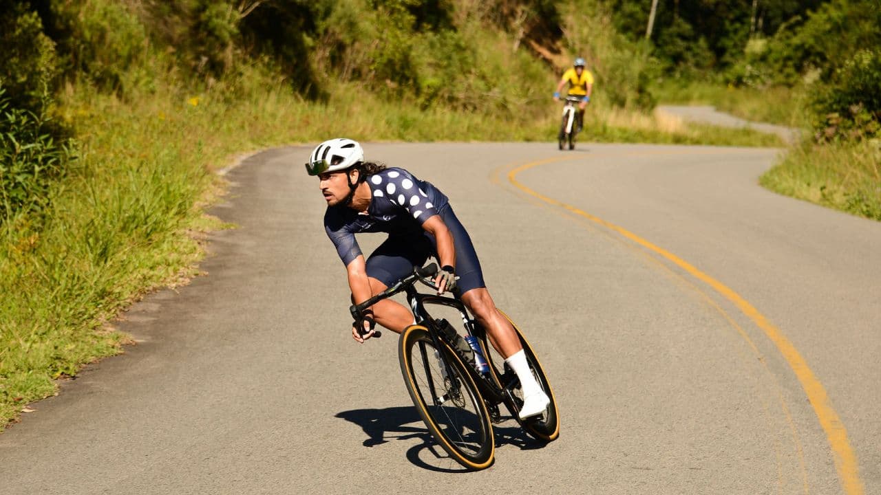 Triathlete completing steady hill intervals on a road bike to improve lactate threshold, leg strength, and cycling endurance.