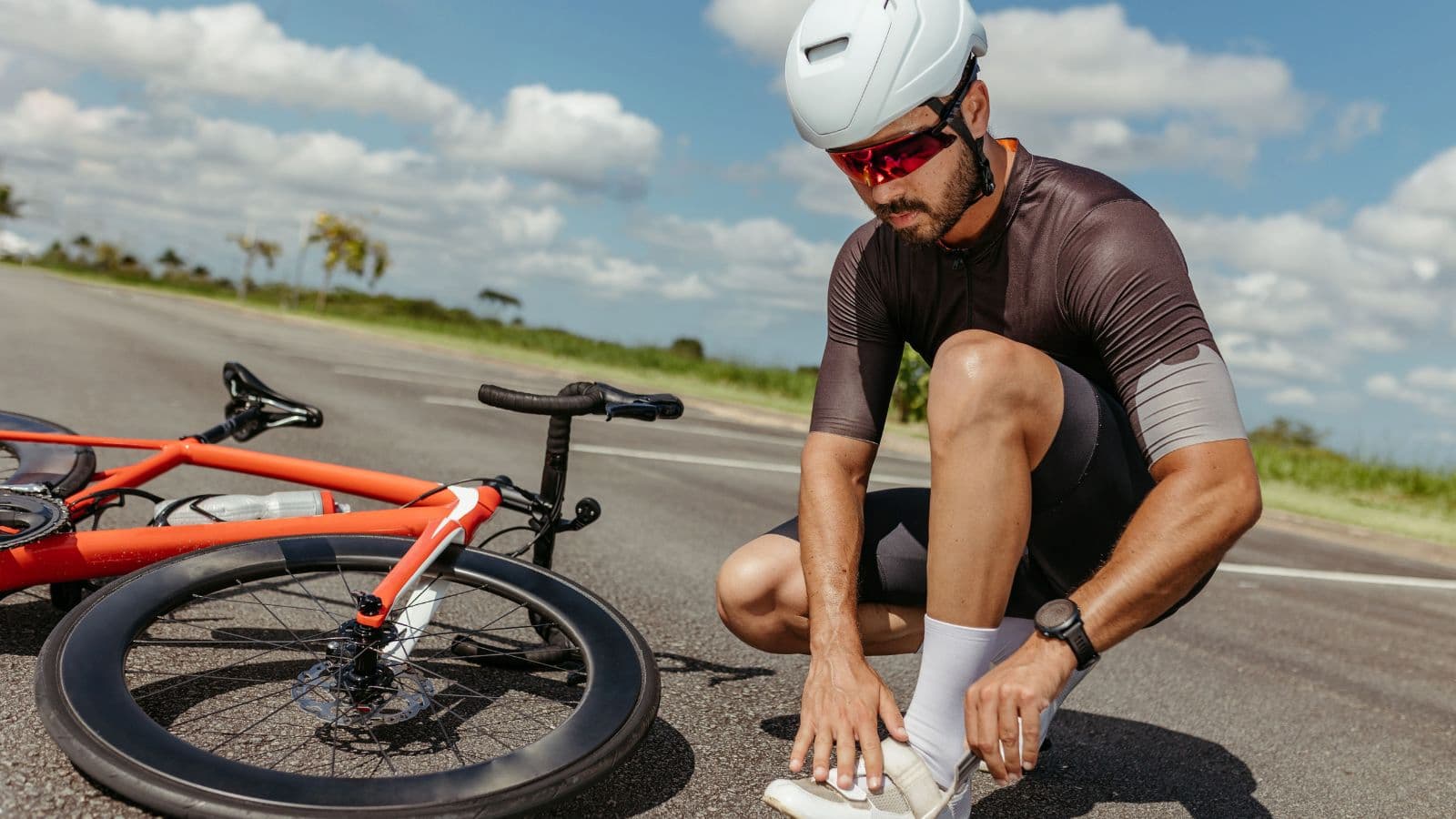 Triathlete loosening cycling shoe dials and straps to relieve pressure on the feet during a long road cycling ride.