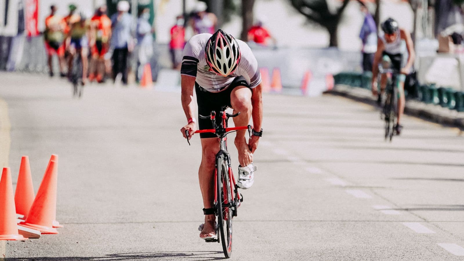 Triathlete rubbing a burning, painful foot after experiencing hot foot during a long-distance cycling training session.