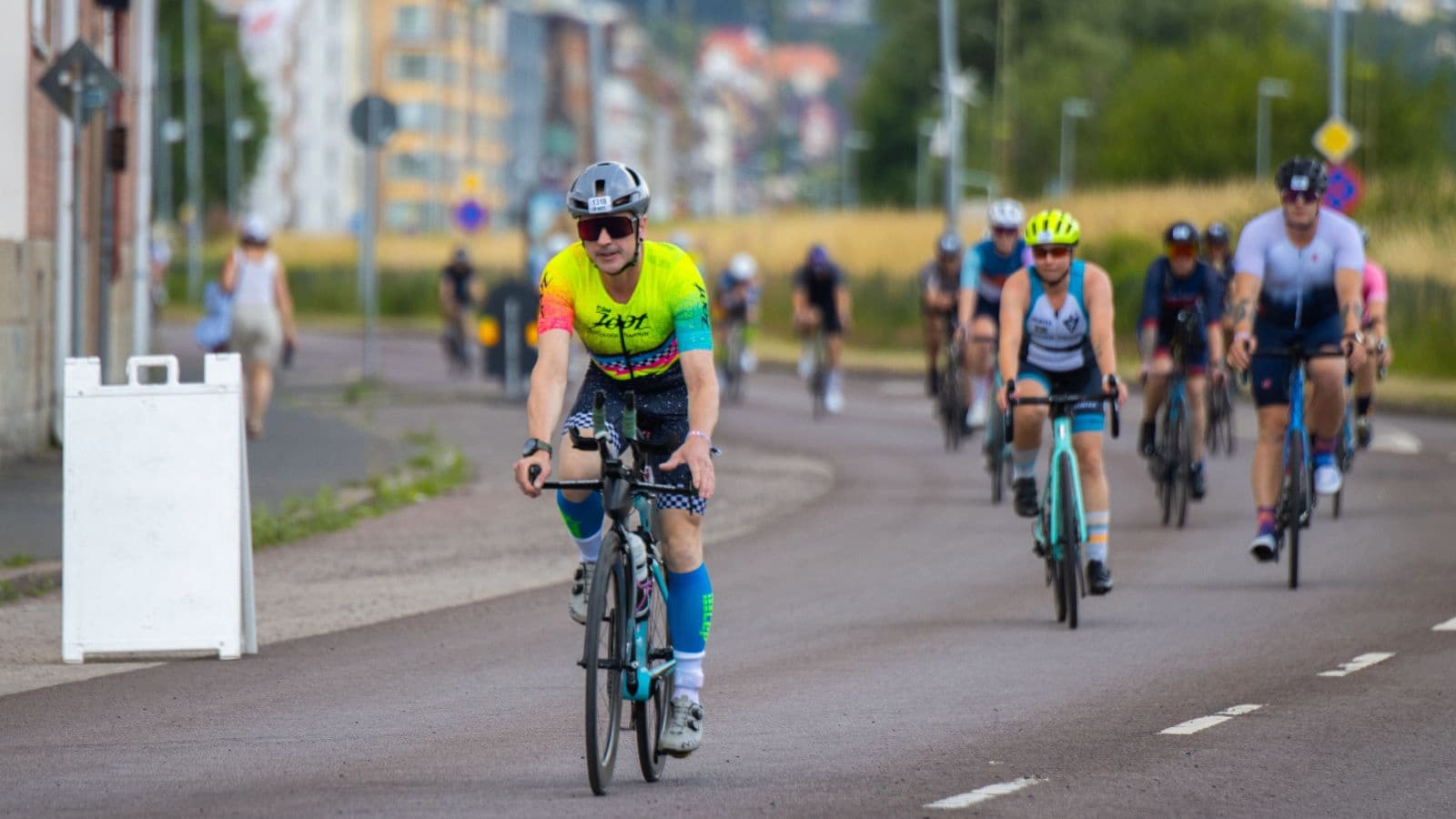 Group of cyclists riding together at varying cadences during a triathlon race on an open road