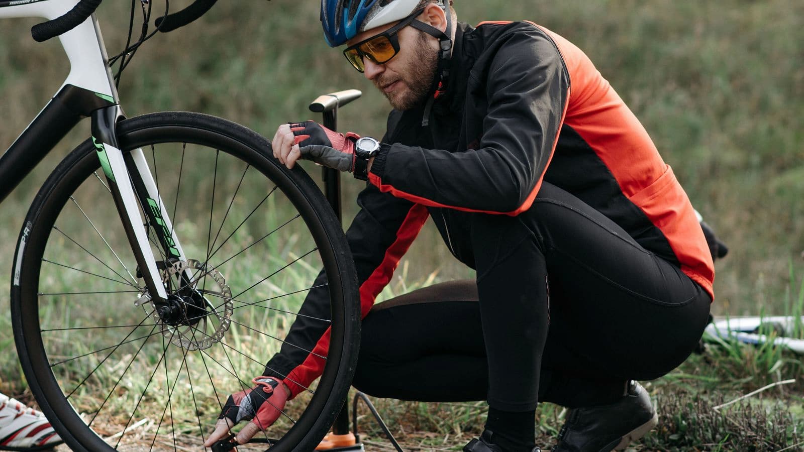 Triathlete repairing a punctured road bike tyre at the roadside using tyre levers and a spare inner tube.
