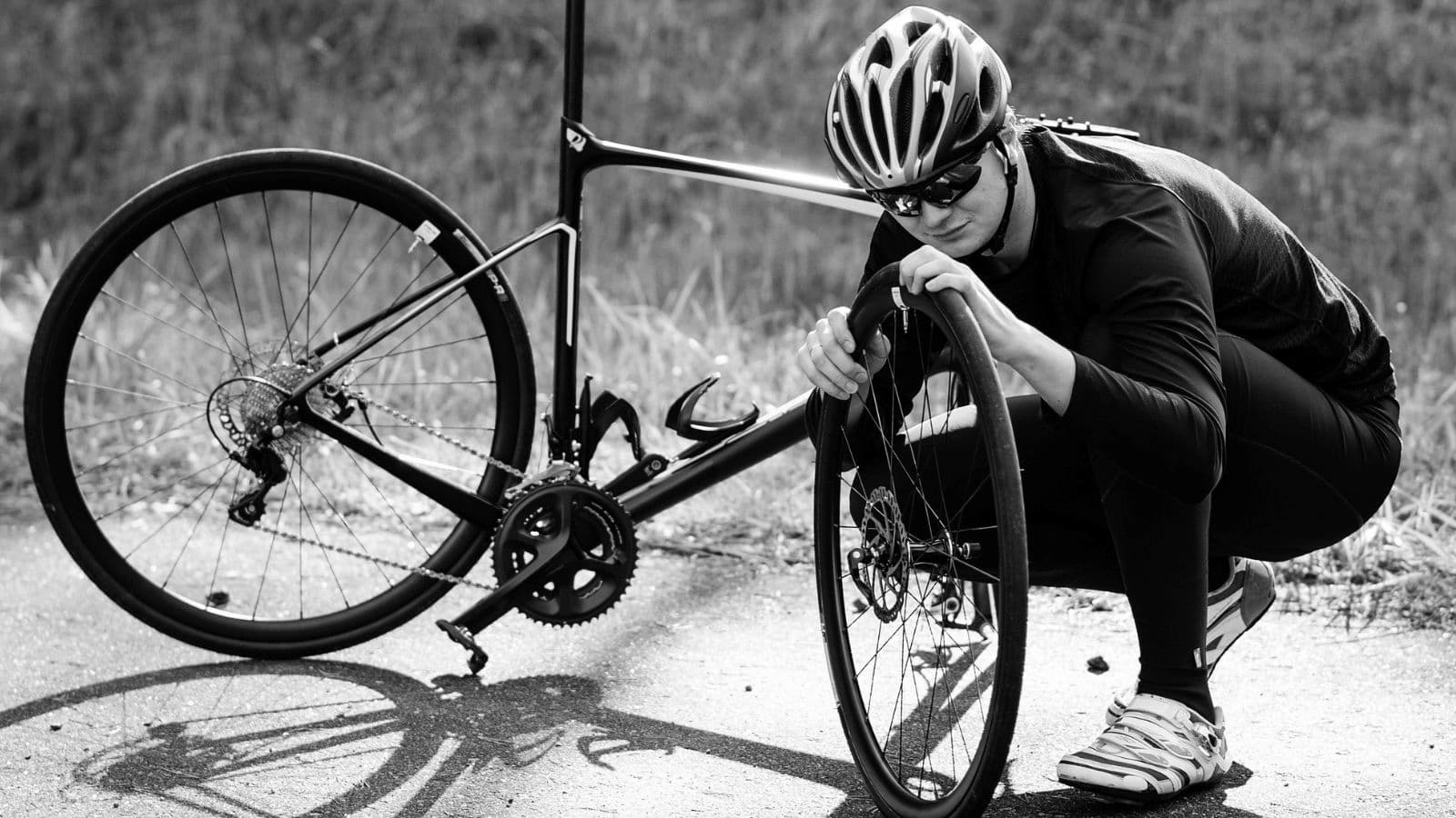 Cyclist carefully checking the inside of a road bike tyre for glass, thorns, or sharp debris before installing a new inner tube.
