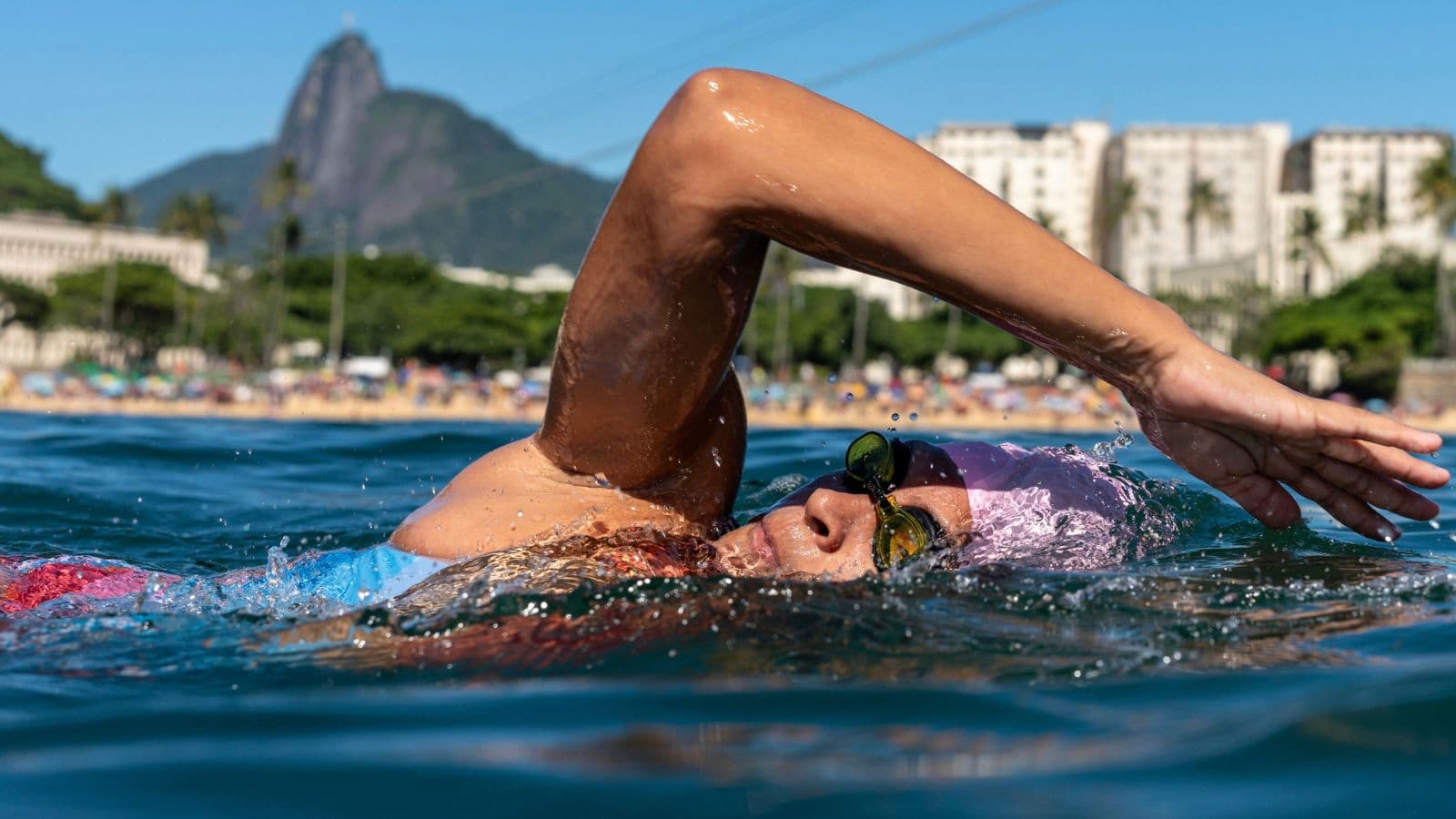 Triathlete swimming in open water during a race while practicing sighting, pacing, and efficient freestyle technique.