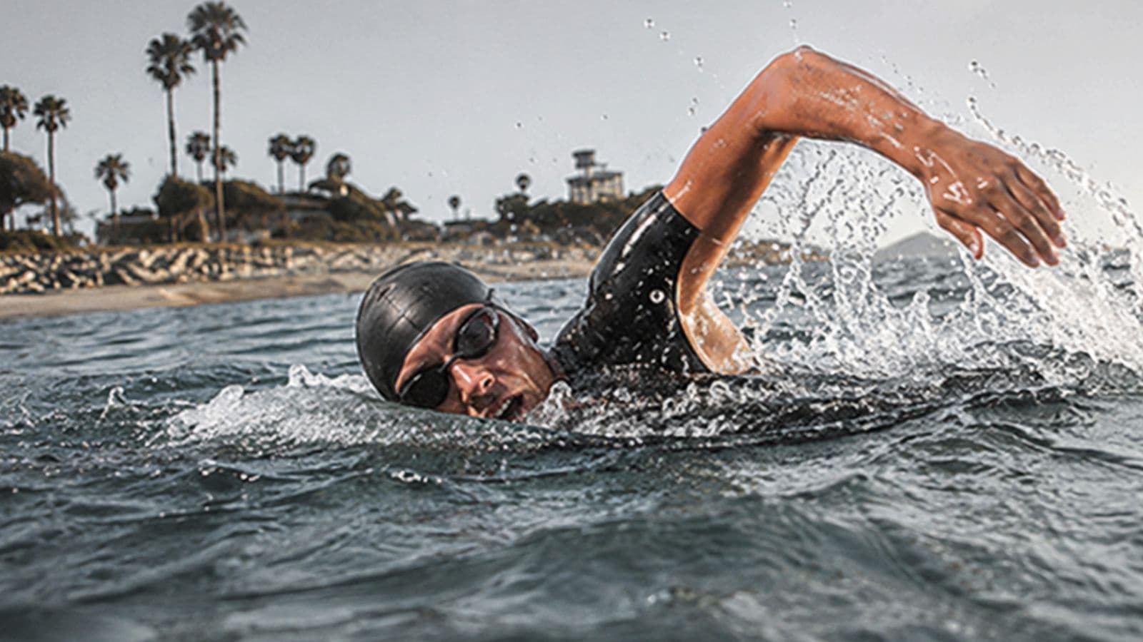 Triathlete drafting behind another swimmer during an open-water triathlon swim to reduce resistance and improve swimming efficiency.