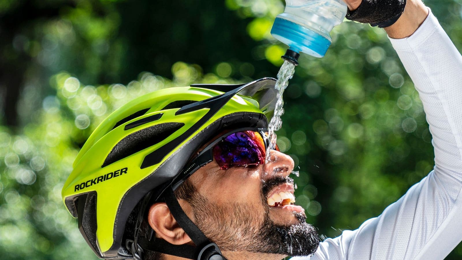 Triathlete cycling on a sunny road while following a hydration strategy to prevent dehydration during hot-weather training.