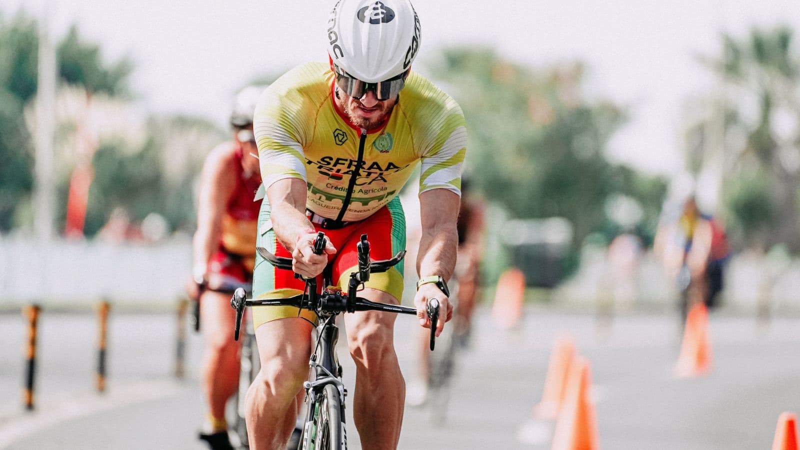 Triathlete cycling at high speed during a triathlon race with aerodynamic positioning and efficient pedaling technique.