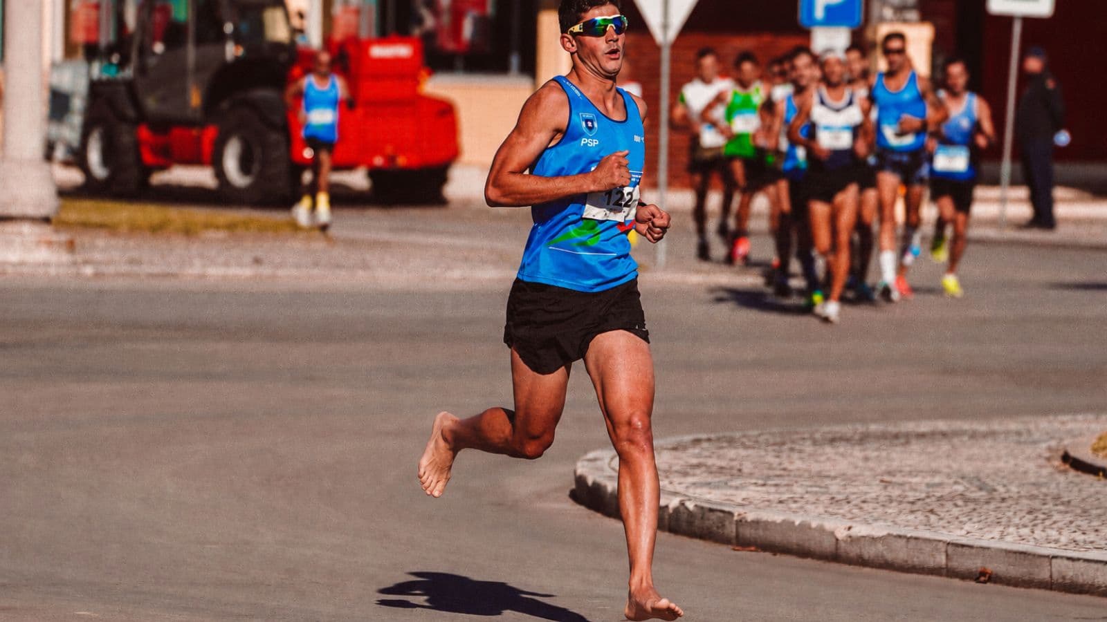 Close-up of a runner landing with a natural midfoot strike while running barefoot on a smooth outdoor surface.