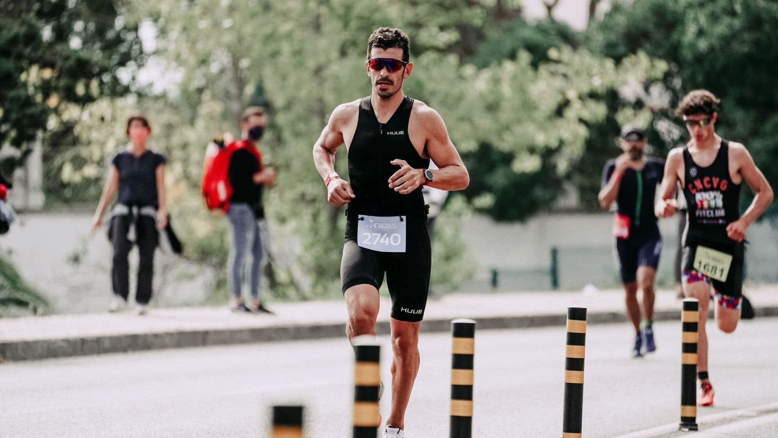 Runner checking smartwatch to maintain steady pace during long-distance training run on a paved trail