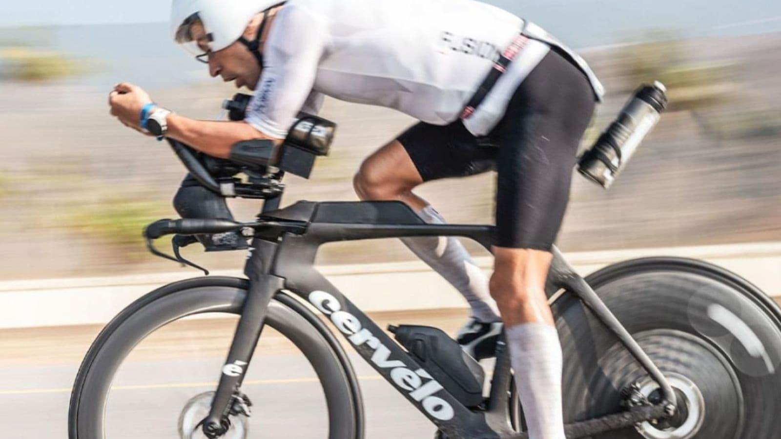 Triathlete descending a winding road on a triathlon bike with a stable body position and controlled speed.