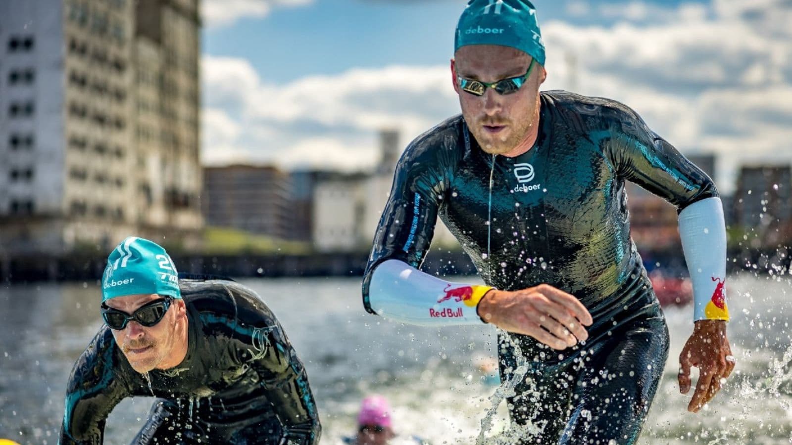 Triathletes positioning themselves across an open-water start line before beginning the swim leg of a triathlon.