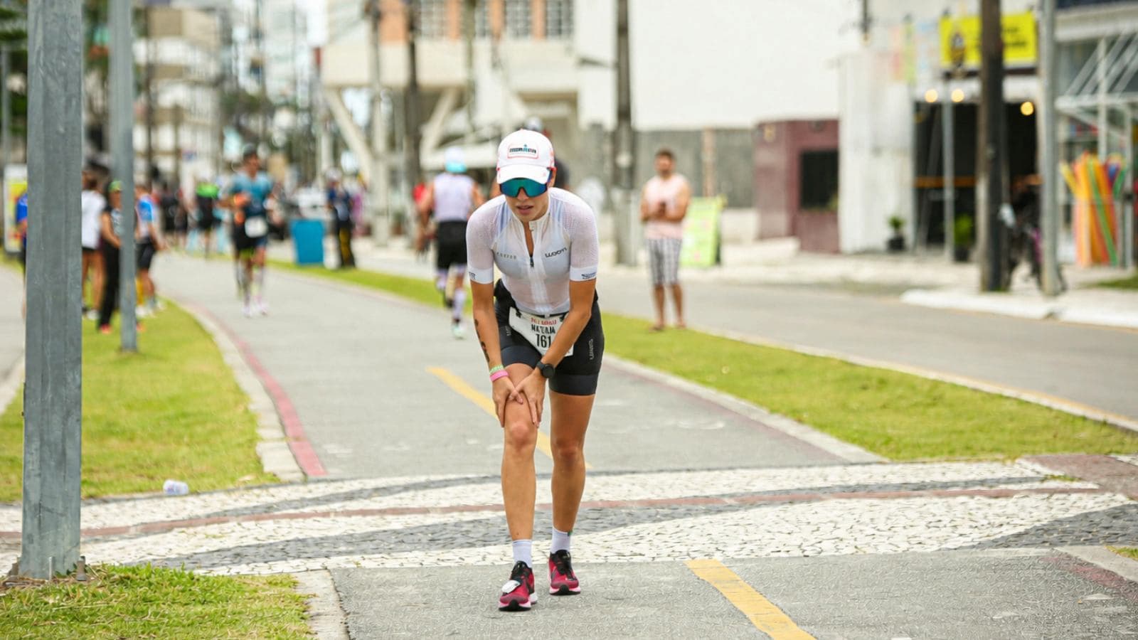 Triathlete holding the area below the kneecap after training where patellar tendon pain commonly develops.