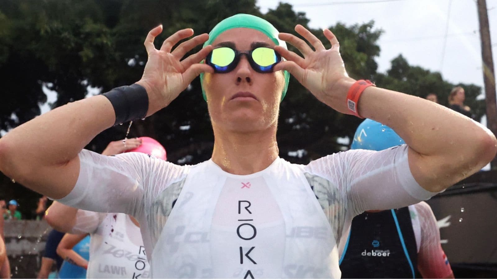 Triathletes entering open water at the start of a race while maintaining controlled effort and positioning.