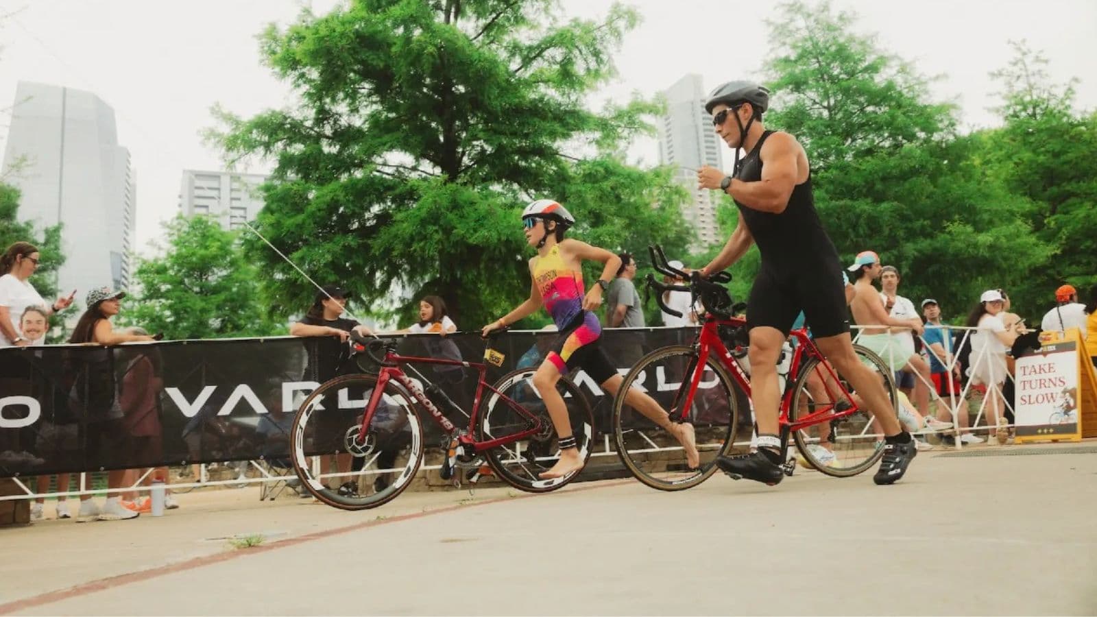 Triathlete arranging cycling shoes, running shoes, helmet, and race equipment beside a bike before a triathlon.