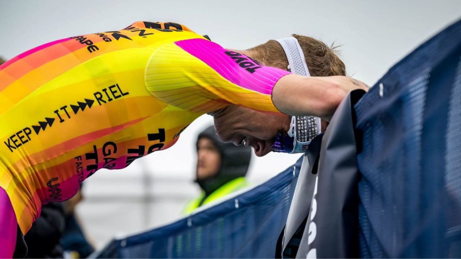Fatigued triathlete stopping at an aid station during a hot race after showing signs of difficulty coping with extreme conditions.