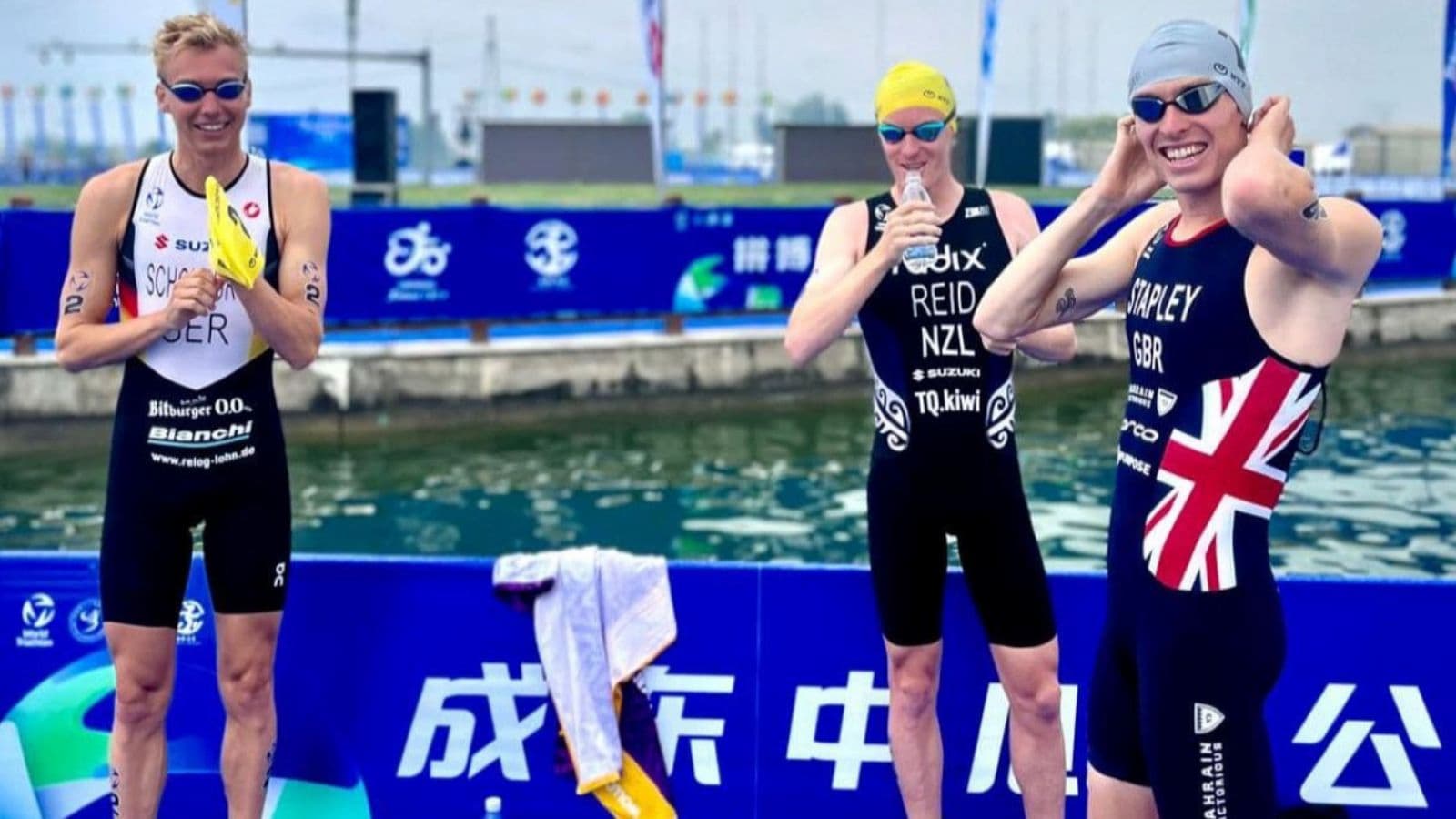 Triathlete keeping equipment organized beside a bike without blocking neighboring athletes in a busy race transition area.