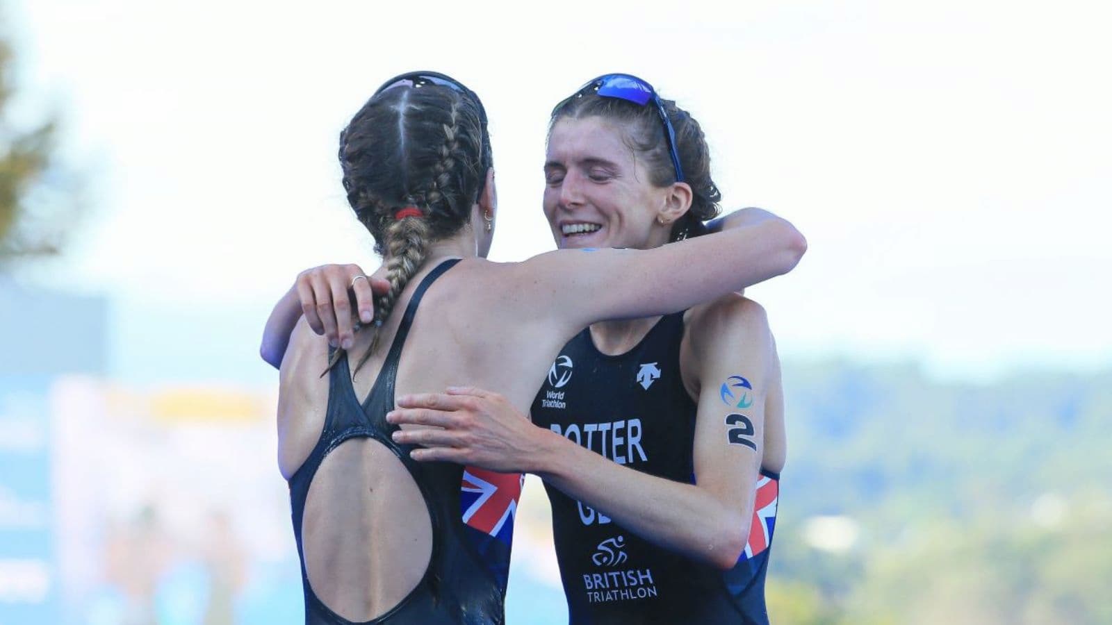 Triathletes congratulating each other after crossing the finish line following a competitive triathlon race.