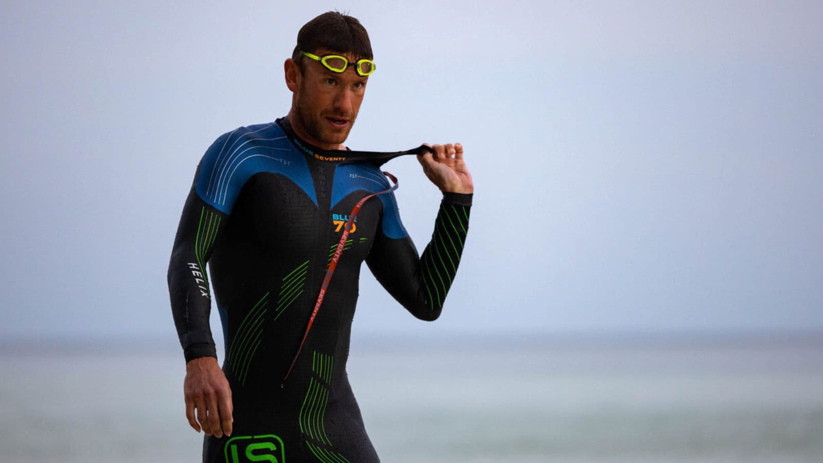 Triathlete inspecting a wetsuit for small tears, cuts, and damaged seams before an open water triathlon race.