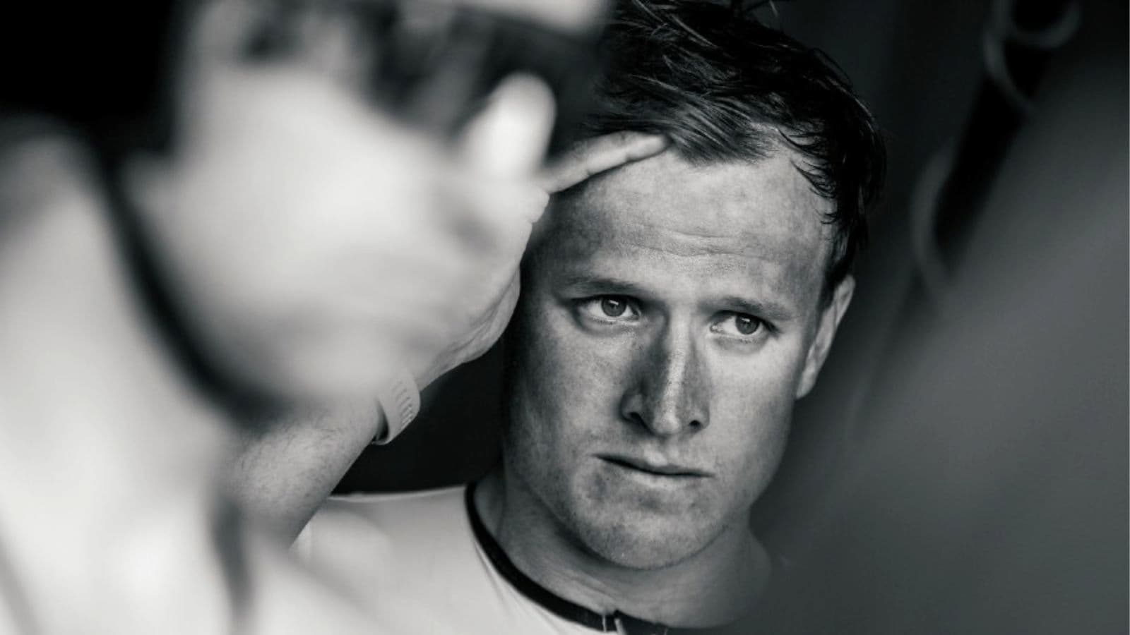 Triathlete applying broad-spectrum sunscreen to exposed skin before an outdoor swim, bike, and run training session.