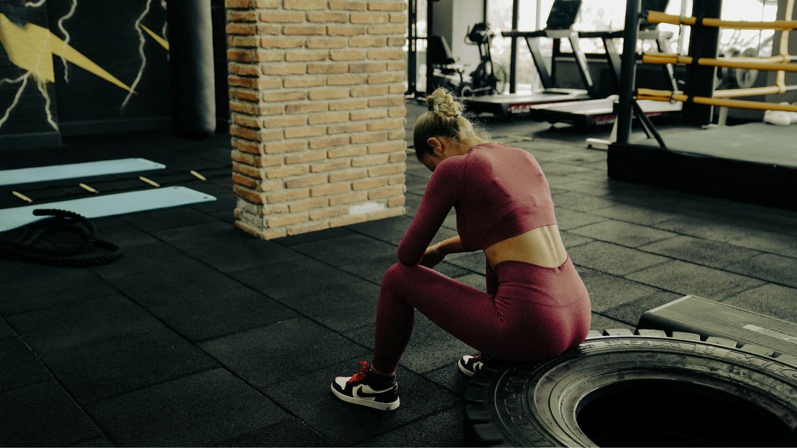 Injured triathlete sitting beside training equipment while taking time away from normal swim, bike, and run workouts.