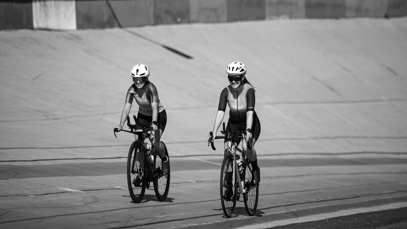 Female triathlete comparing women's cycling saddles with different widths, shapes, and pressure-relief channels at a professional bike fitting studio.